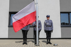 Policjanci wystawiają flagę Polski na maszt