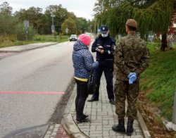 policjant w asyście żołnierza WOT legitymuje kobietę