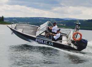 Dwóch umundurowanych policjantów na policyjnej łodzi na wodzie.