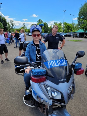 chłopiec siedzi na motorze policyjnym w czapce policyjnej