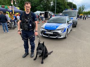 policjant z psem słuzbowym przy radiowozie
