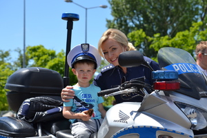 Policjantka przytrzymuje dziecko siedzące na motocyklu policyjnym