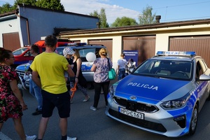 dzieci i rodzice stojący przy radiowozach