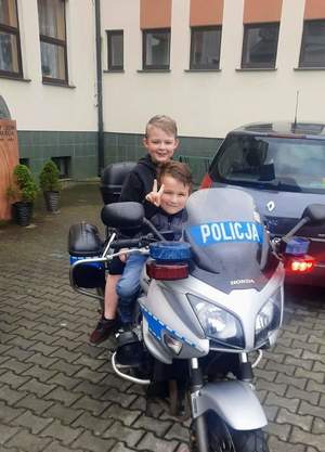 Na motocyklu policyjnym siedzi dwoje dzieci.