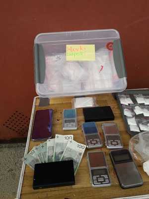 plastykowy pojemnik z napisem worki dilpaki, foliowe woreczki z amfetaminą, banknoty, telefony komórkowe