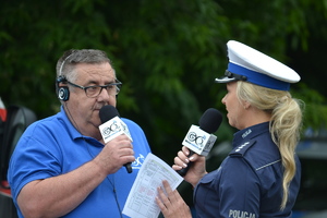 Policjantka ruchu drogowego oraz dziennikarz z GO+ Motoradio rozmawiają ze sobą trzymając mikrofony z logiem radia.
