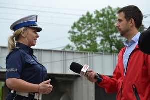 Policjantka ruchu drogowego udziela wywiadu dziennikarzowi który trzyma w ręce mikrofon z napisem TVP INFO.