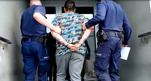 Dwaj umundurowani policjanci wprowadzają do budynku Komendy podejrzanego o zabójstwo mężczyznę.