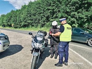 policjant z drogówki rozmawia z motocyklistą, obok zaparkowany motocykl
