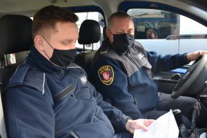 policjant i strażnik miejski w radiowozie podczas wspólnego patrolu