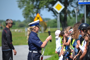 Policjantka ruchu drogowego prowadzi prelekcję w plenerze dla dzieci