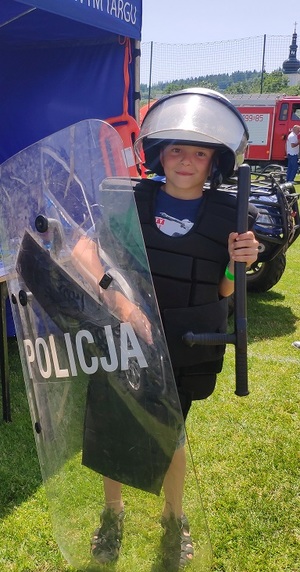 chłopiec w kaskiem i tarczą z napisem policja