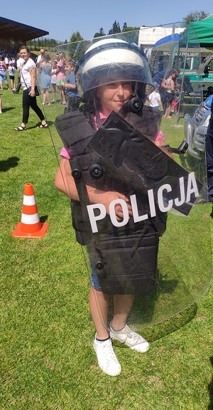 chłopiec w policyjnym ubraniu z tarczą z napisem policja