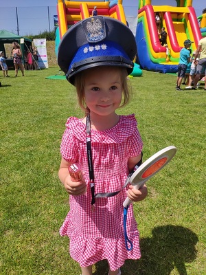 dziewczynka w różowej sukience z czapka policyjną na głowie