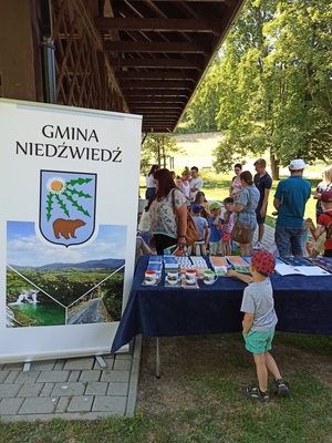 Uczestnicy imprezy plenerowej przy stanowisku Gmina Niedźwiedź  podczas imprezy plenerowej „Niedziela w Gorczańskim Parku Narodowym”.