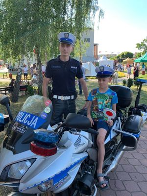 policjant ruchu drogowego wraz z chłopcem siedzącym na policyjnym motorze