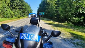 policyjny motocykl na pierwszym planie, w tle punkt startowy jednego z biegów