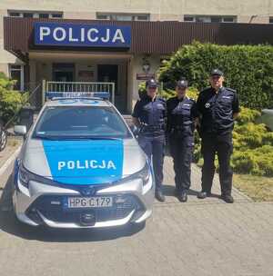 troje policjantów stojących przy radiowozie