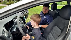 policjant i chłopiec w radiowozie, maluch trzyma kierownicę w dłoniach