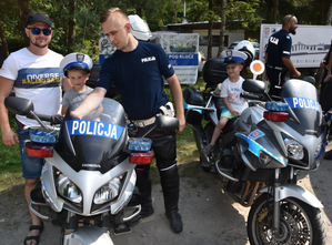 Umundurowani policjanci oraz dzieci siedzące na motocyklach z napisem POLICJA