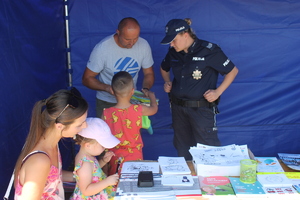 policjant przy stoisku profilaktycznym, obok dzieci i dorośli