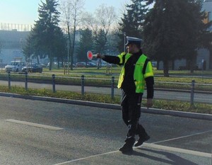 policjant ruchu drogowego na jezdni z tarczą do zatrzymywania pojazdów