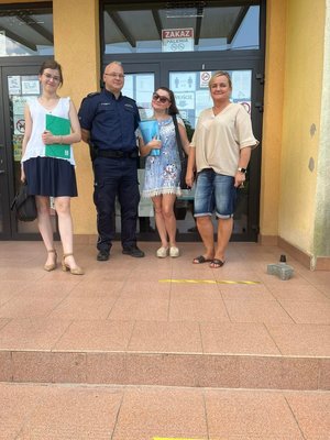 wspólne zdjęcie przed budynkiem policjanta oraz trzech kobiet z instytucji uczestniczących w kontroli placówek zorganizowanego wypoczynku dla dzieci