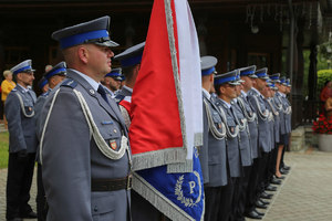 Poczet sztandarowy i policjanci oczekujący do awansu