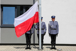 Policjanci rozkładają polską flagę na maszcie