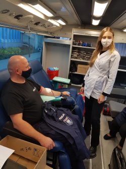 policjant w mobilnym punkcie oddaje krew, a obok pielęgniarka