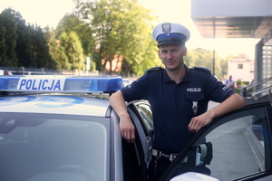 Policjant przy radiowozie BMW oparty o drzwi