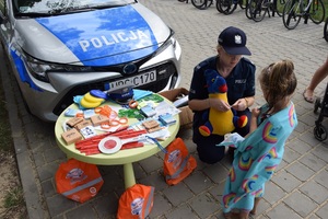 policjantka przy radiowozie rozmawia z małą dziewczynką