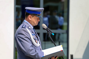 policjant przy mikrofonie podczas uroczystego apelu z okazji otwarcia nowego budynku Komisariatu Policji w Wojniczu