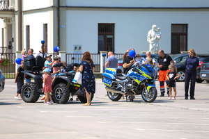 policyjny motocykl i quad na którym siedzą dzieci, obok stoja inne osoby i policjanci