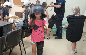 dzieci odwiedzające komisariat przymierzają elementy umundurowania policjantów