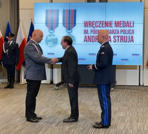 Mister Kamiński i nadinsp. Jarsoław Szymczyk wręczają medal policjantowi