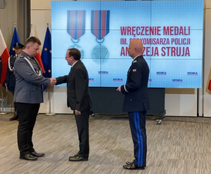 Mister Kamiński i nadinsp. Jarsoław Szymczyk wręczają medal policjantowi