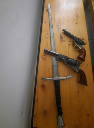 dwa pistolety i miecz leżące na biurku