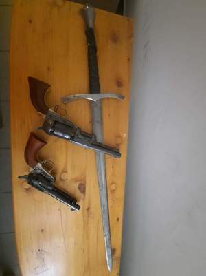 dwa pistolety i miecz leżące na biurku