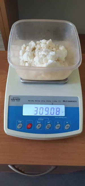 na szafce stoi waga, na wadze w pojemniku biały granulat