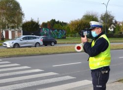 policjant z laserowym miernikiem prędkości, obok przejście dla pieszych