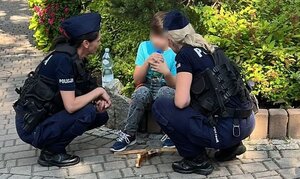 Oliwier siedzi na murku, przy nim są policjantki