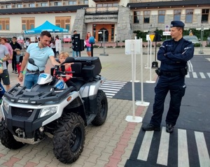policjant przy policyjnym Quadzie, obok uczestnicy festiwalu
