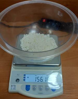 waga elektroniczna ze szklanym pojemnikiem w którym znajdują się białe kryształki- narkotyki