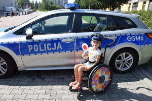 Dziewczynka na wózku inwalidzkim na tle radiowozu