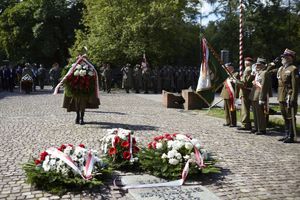 Zołnierze składają wieniec przed pomnikiem. Za nimi stoją zaproszeni goście