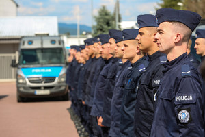 policjanci oddziału prewencji w szeregu w tle i radiowóz
