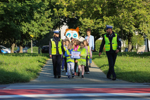 dzieci przechodzą przez jezdnię przed nimi policjant i policjantka