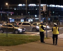 Policjanci wydziału ruchu drogowego stoją na chodniku przy ulicy