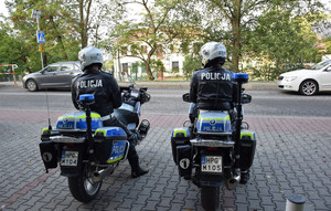 policjanci na motorach zaparkowanych przy drodze przed szkołą